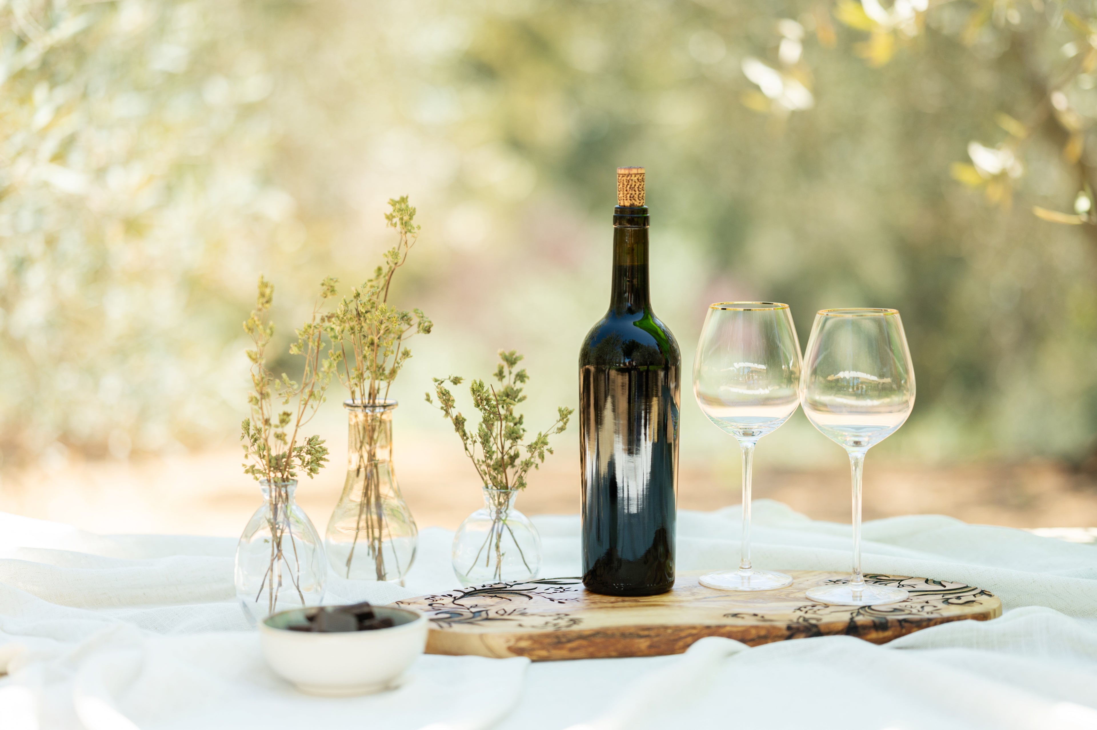 Wine bottle and glasses on a wooden board with a blurred natural background