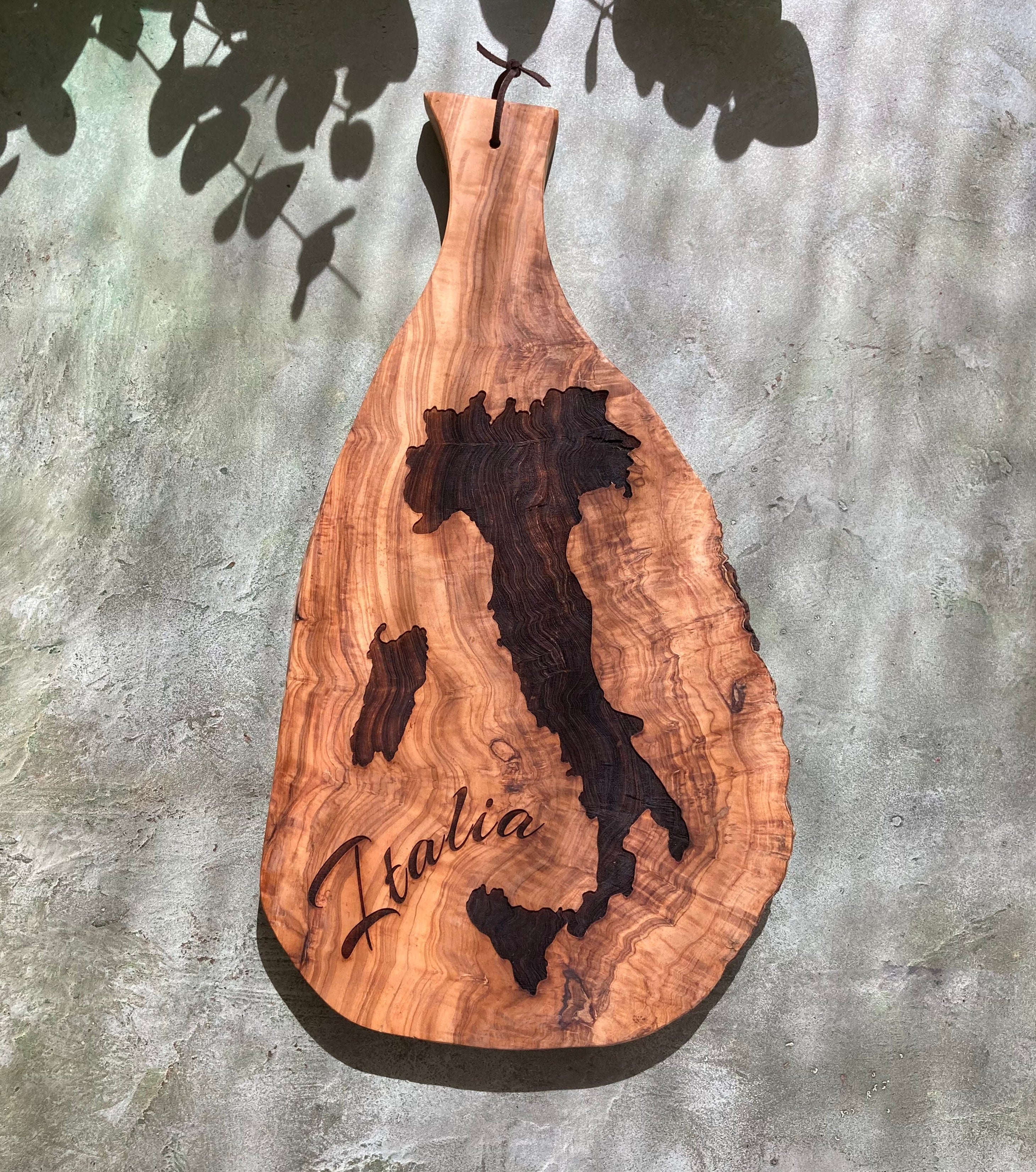 Wooden paddle with laser-cut map of Italy and 'Italia' engraving on a textured wall background